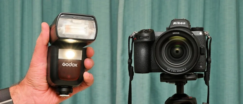Спалах Godox V860III з прямокутною головкою Френеля та увімкненим круглим світлодіодним пілотним світлом 2W поруч із камерою Nikon на штативі